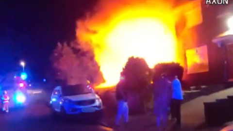 A CCTV image showing a large orange and yellow glow outside a terraced house as neighbours and firefighters look on