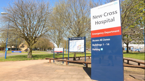 General view of the entrance of New Cross Hospial . on the right of the picture is a sign that reads New Crowss Hospital and trees can be seen in the background