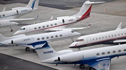 Generic image of several white private jets on the ground at an airport