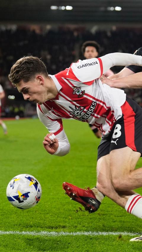 Footballer falls forward towards the ball.