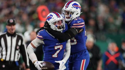 Taron Johnson holds the football and is hugged by Terrel Bernard