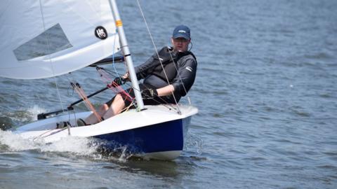 Man steering a sailing boat on a lake