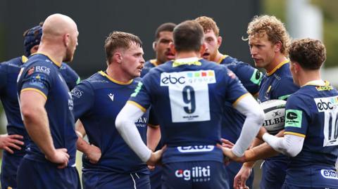 Worcester Warriors players have a talk in a team huddle during a game