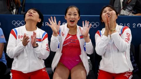 Flanked by two coaches, An Chang-ok waves for the camera