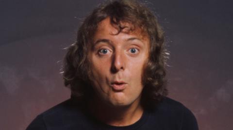 Jasper Carrott, with curly hair, wearing a black T-shirt.