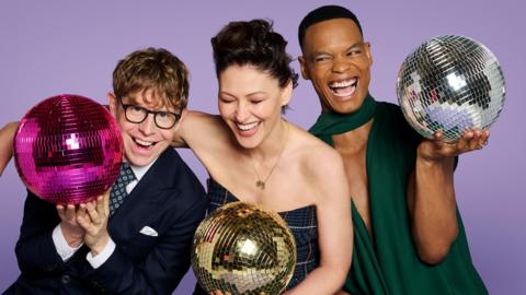 Johannes Radebe, Emma Willis and Josh Widdicombe holding disco balls