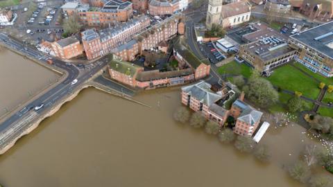 An aerial view shows the town of Worcester submerged in floodwater with cars driving along a bridge on 9 February.