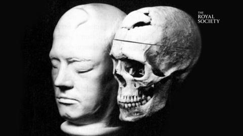 Image of a death mask and a skull on a black background