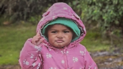 Tavia Da Costa wearing a pink coat with flowers on it and a green hat underneath. 