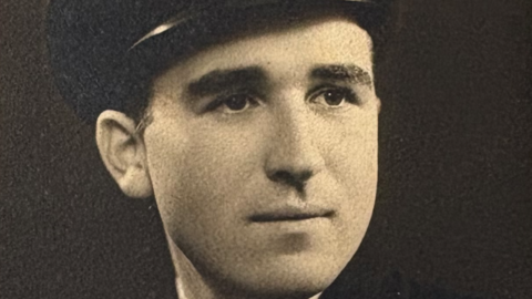 A black and white photo of a young man in military uniform. He is wearing a cap.