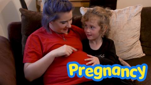 Pregnant mother with daughter, daughter is touching baby bump.