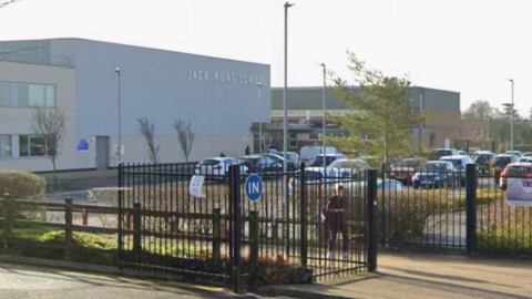 Google street view image of Jack Hunt- a big white building with Jack Hunt written on it in silver and black gates in front leading to a car park.