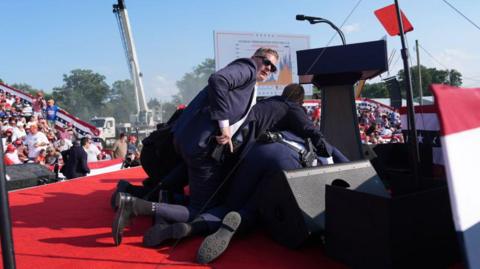  Secret service agents cover former president Donald Trump during a campaign rally for former President Donald Trump at Butler Farm Show Inc. on Saturday, July 13, 2024 in Butler, Pa