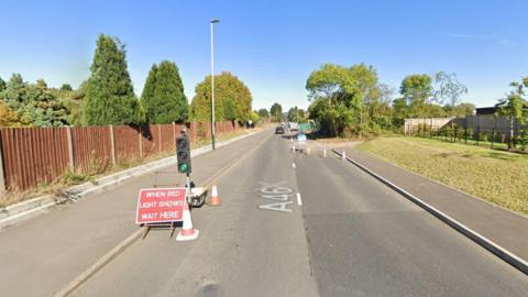 A screengrab of Google Maps which shows the A46 Shurdington Road. A temporary traffic light is in place which says 'when red light shows wait here'.