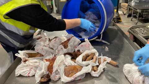 Man in high vis vest pulls packets of sausages and meat out of blue holdhall