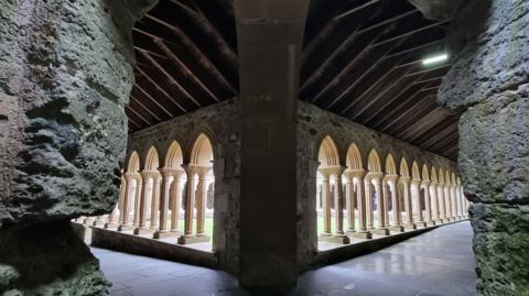 Panoramic image of arches in the Abbey, framed by old stone walls