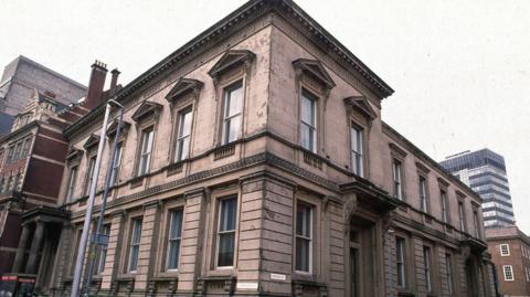 Birmingham Magistrates' Court. Brown building on the corner of the road with another building behind it. 