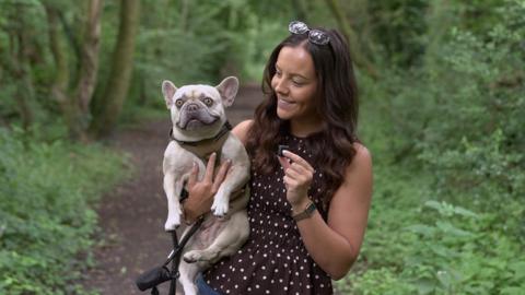 women holding dog in her arms in the woods