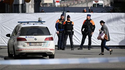 Police outside a cordon surrounding the scene of a bombing.