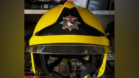 A yellow Norfolk Fire and Rescue Service helmet sat on a locker shelf