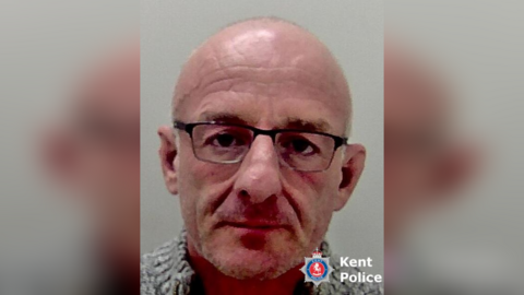 A police mug shot of a bald man. 