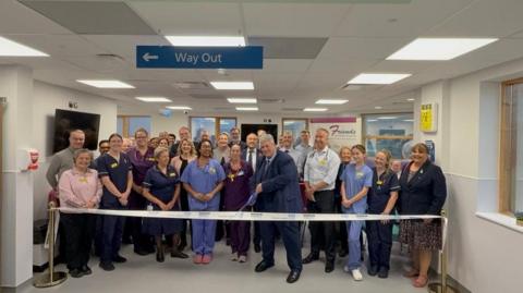 Julian Parfitt, surrounded by dozens of members of staff, cuts the ribbon to officially open the new unit.