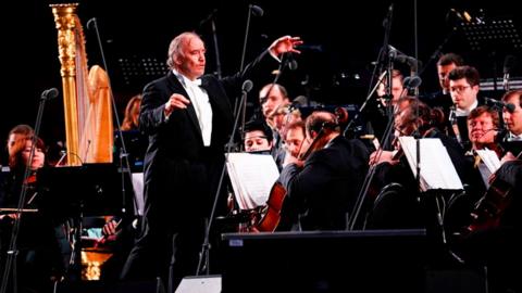 Russian conductor and Mariinsky Theater Artistic Director Valery Gergiev is surrounded by classical musicians on stage in Moscow in 2018. 