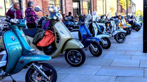 Line of scooters parked along a pavement