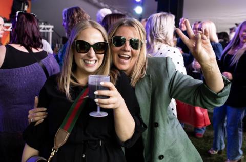 Two women in sunglasses smile at the camera at one of the smaller stages at the Cheltenham Jazz Festival