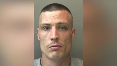 Police custody picture of Scott Marriott. He has very short, dark brown hair and is looking directly at the camera.