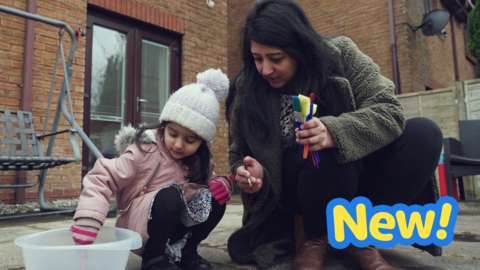 A mum and daughter painting with water on the patio floor.
