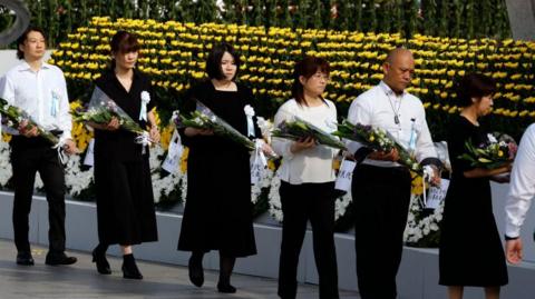 Attendees offer flowers during the Peace Memorial Ceremony on the 80th anniversary of the atomic bombing of Hiroshima
