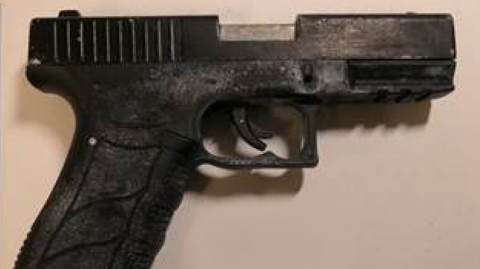 A black handgun, set against a beige background.