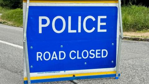 A blue police road closed sign.