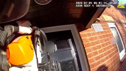 A chainsaw is being used to break through a grey front door