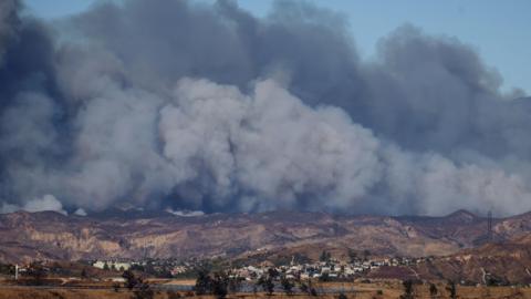 Smoke plumes can be seen billowing in the sky near communities in Los Angeles county 