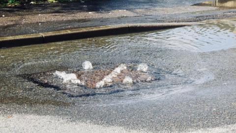 Water gushing out of a manhole cover