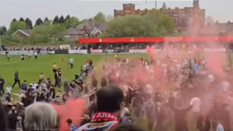 Fans look on from the stands as supporters ran onto the pitch and let off flares