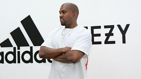 Kanye West in front of Adidas and Yeezy branding