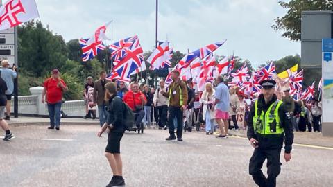 Men and women protesting immigration in Bournemouth. One police office present.
