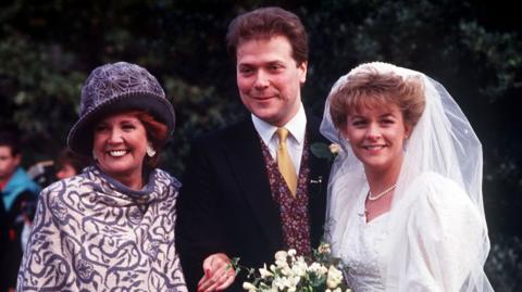 Sue and Alex Tatham on their wedding day, alongside guest Cilla Black