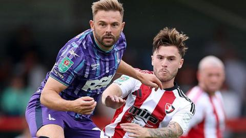 Matthew Godden (left), of Charlton Athletic, battles for the ball with Cheltenham Town's Charlie McCann