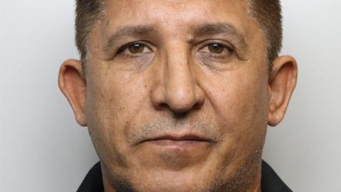 A mugshot of Mohammed, who has short, dark hair that is neatly trimmed and evenly cut across the top and sides. His face is fully visible, with symmetrical features, dark eyebrows, and eyes looking directly toward the camera. His facial hair is minimal, with slight stubble visible around the chin and jawline area.