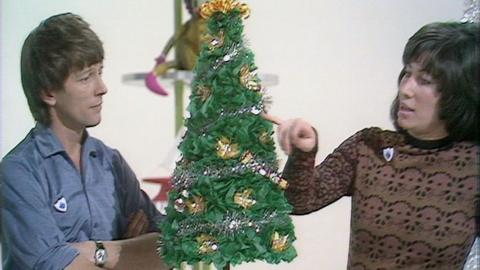 John and Val stand beside a Christmas tree made from tissue paper