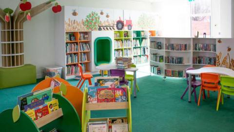 A young person's area in a library, with children's books and tables