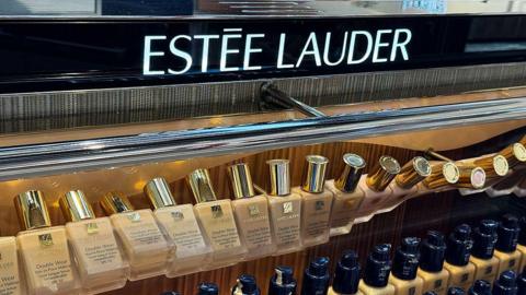 A row of Estee Lauder cosmetics on a shop shelf, the brand name above them.