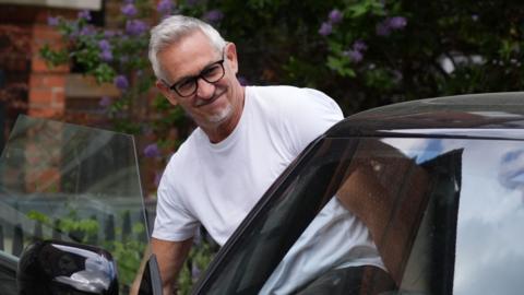 Gary Lineker is smiling as he gets into his car.