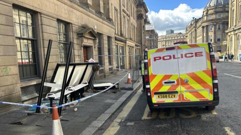 Broken bus stop and police van next to it on a sunny day