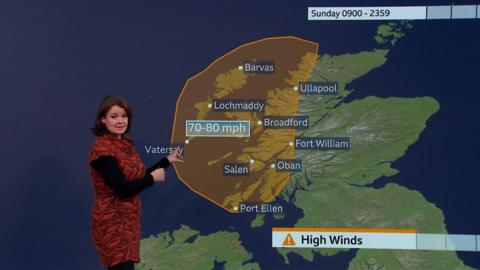 Gillian Smart wears a red and black dress. She presents the weather in front of a green screen which forecasts high winds across Scotland. 