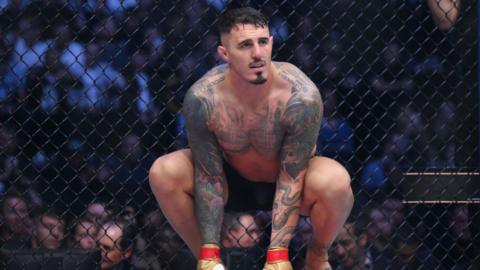 Tom Aspinall crouches in the octagon before a fight